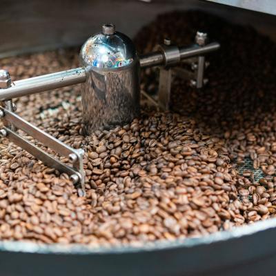Close-up of coffee beans being roasted in a metal roaster, highlighting freshness.